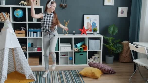 Teenagermädchen tanzen und genießen es, zu Hause Musik über Kopfhörer zu hören — Stockvideo