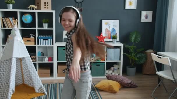 Zeitlupe glücklicher tanzender Kinder, die Spaß an Musik mit Kopfhörern in der Wohnung haben — Stockvideo