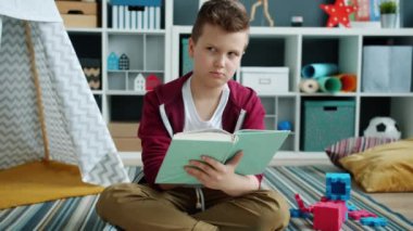 Akıllı çocuk kitap okuyor evde oturmuş edebiyat ve eğitimin tadını çıkarıyor.