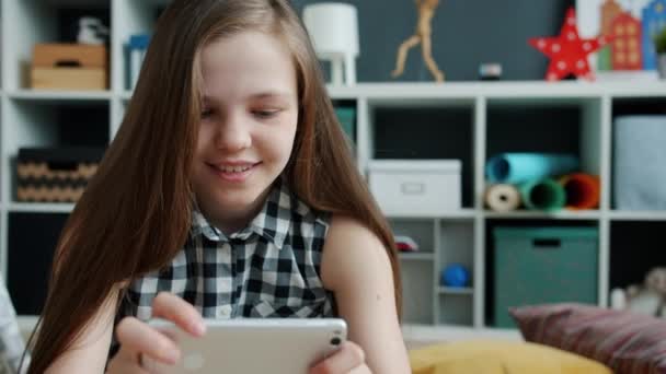 Cámara lenta de chica feliz disfrutando de videojuego con teléfono inteligente sonriendo pantalla táctil en casa — Vídeos de Stock