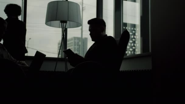 Silhouettes d'hommes d'affaires utilisant des ordinateurs et parlant sur un téléphone portable à l'intérieur dans le hall de l'hôtel — Video