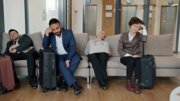 Портрет втомлених бізнесменів у формальному одязі, що спить на дивані у вестибюлі — стокове відео