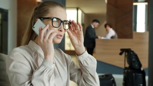 Piękna młoda dama rozmawiająca przez telefon komórkowy w nowoczesnym hotelowym lobby — Wideo stockowe