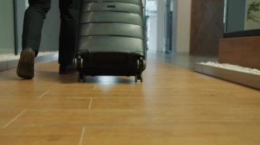 Otel resepsiyonuna bavulla giden adamın bacakları ağır çekimde.