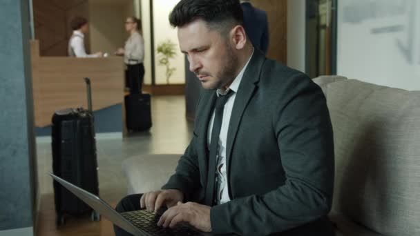 Középkorú vállalkozó dolgozik laptop a szálloda halljában gépelés elfoglalt a munkával — Stock videók
