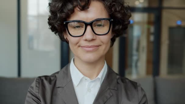 Retrato de cerca de una mujer de negocios guapa con gafas sonriendo en el vestíbulo del hotel — Vídeos de Stock