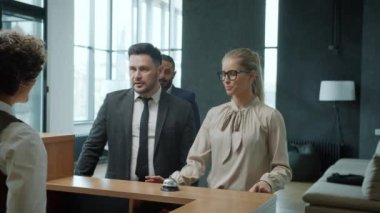 Neşeli çift resepsiyonistle konuşuyor anahtar kartı alıyorlar sonra da bavullarla odaya giriyorlar.