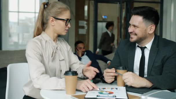 Munter mand og kvinde diskuterer forretning sidder i hotellets hal ved bordet med papirer – Stock-video