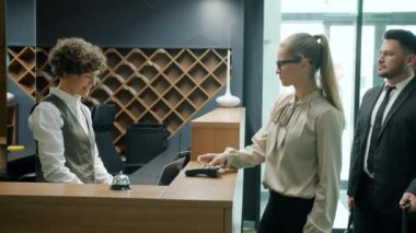 Otel müdürü online ödeme alan müşterileri karşılıyor lobide anahtar kartları veriyor