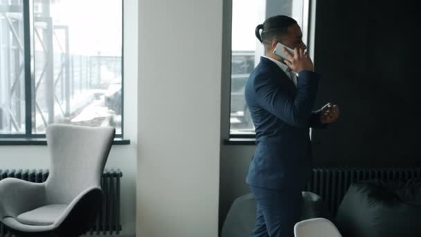 Succesvolle ondernemer in pak spreekt op mobiele telefoon lopen binnen in kantoor — Stockvideo