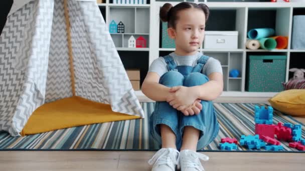 Μοναχικό κοριτσάκι που κάθεται στο πάτωμα και αναστενάζει νιώθοντας αναστατωμένη και προσβεβλημένη μόνη στο σπίτι. — Αρχείο Βίντεο