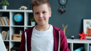 Dairede durup kameraya gülümseyen bir çocuğun ağır çekim portresi.