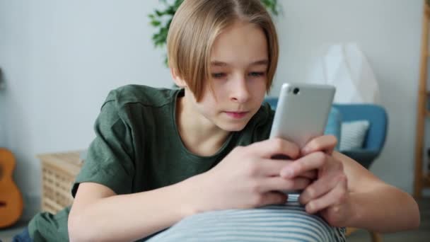 Joyeux adolescent textos avec smartphone jouissant de la communication sur les médias sociaux dans l'appartement — Video