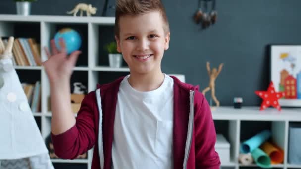 Portret van vrolijk kind zwaaiende hand en glimlachend kijkend naar camera in appartement — Stockvideo