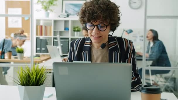 Muotokuva houkutteleva nainen Call Center työntekijä puhuu soitto ja kirjoittaminen kannettavan tietokoneen työpaikalla — kuvapankkivideo