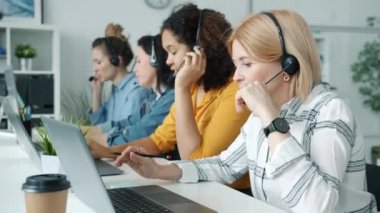 Bir grup kadın, ofiste çalışan, kulaklık ve dizüstü bilgisayarla konuşan merkez çalışanlarını arıyor.