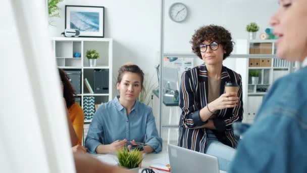 Gravi impiegati che ascoltano le donne che fanno presentazioni con la lavagna sul posto di lavoro — Video Stock