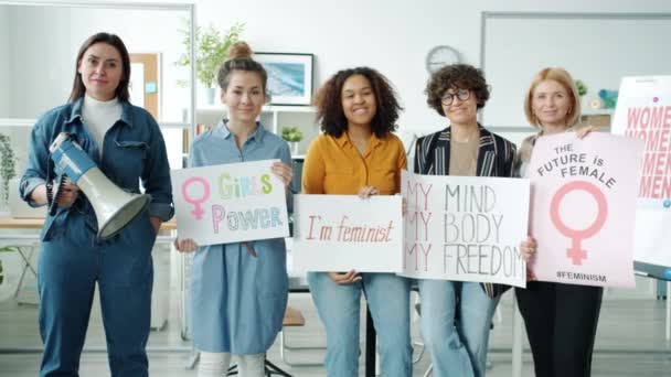 Zpomalený portrét žen feministky stojící v interiéru držící transparenty a reproduktor — Stock video