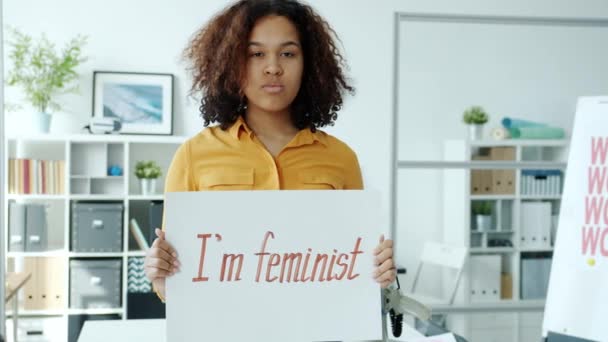 Ciddi bir Afrikalı Amerikalı kadının feminist posteriyle içeride durması ağır çekim. — Stok video