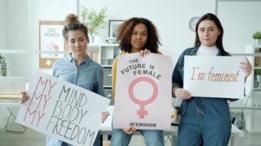 İçerideki kameraya gülümseyen posterlerle mutlu feministlerin ağır çekimleri.