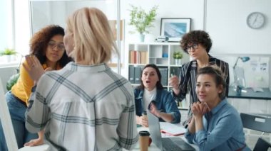 Cam duvar ofisinde sunum yapan bir kadınla konuşan yaratıcı bir ekip.