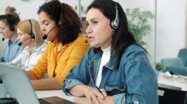 Çağrı merkezi çalışanlarından oluşan çok ırklı bir grup. Kulaklıkla konuşuyorlar, dizüstü bilgisayarla yazıyorlar ve notlar alıyorlar.