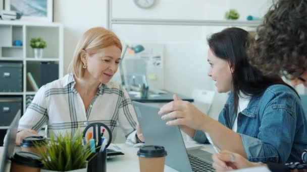 Vrolijke vrouwen praten en het gebruik van laptop werken binnen in licht kantoor — Stockvideo