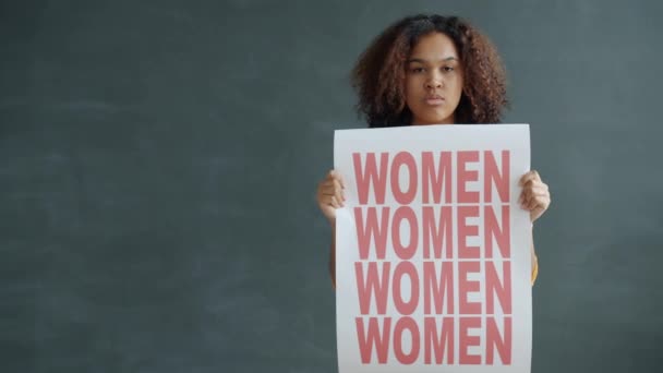Portret van een onafhankelijke Afro-Amerikaanse dame met empowerment banner voor vrouwen op zwarte achtergrond — Stockvideo