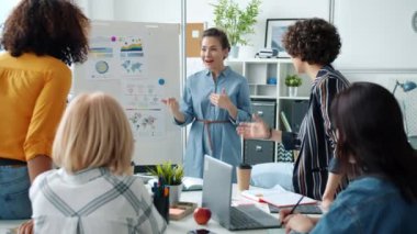 Neşeli genç iş kadını, yönetim kuruluyla iş arkadaşlarına iyi haberler veriyor.