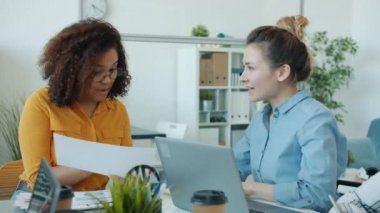 Neşeli Afro-Amerikan ve Asyalı kadınlar fikirlerini paylaşıyor ofiste işbirliğinin keyfini çıkarıyorlar