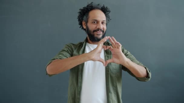 Portrait of loving Middle Eastern guy showing beating heart gesture smiling looking at camera — Stock Video