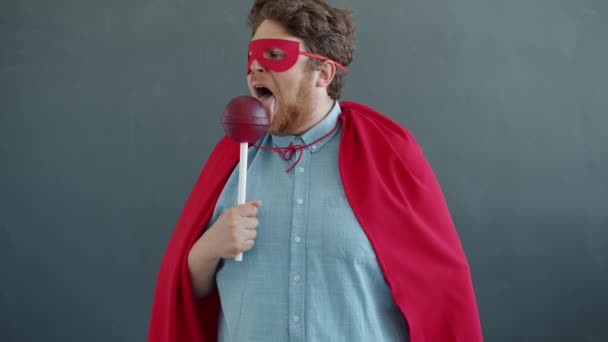 Zpomalený film portrét superman lízání obrovské lízátko křičí ukazující sílu a utíká — Stock video