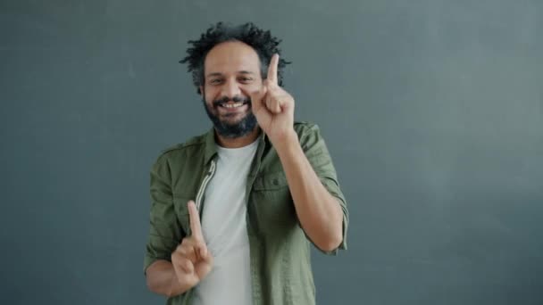 Portrait von glücklichen arabischen Kerl tanzen genießen Musik auf grauem Hintergrund — Stockvideo