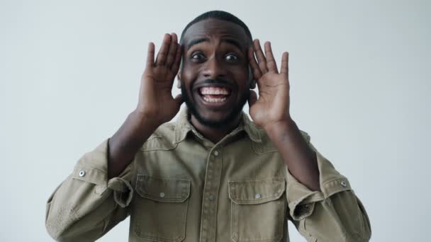 Zeitlupe eines verspielten Afroamerikaners, der sein Gesicht mit Händen bedeckt und entblößt und lustige Fratzen macht — Stockvideo