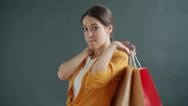 Porträtt av ung dam innehav och kramar shoppingpåsar njuter inköp stående på grå bakgrund — Stockvideo