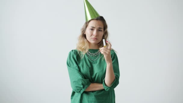 Ritratto di miserabile giovane donna che indossa un cappello da festa che soffia corno con viso triste e deluso — Video Stock