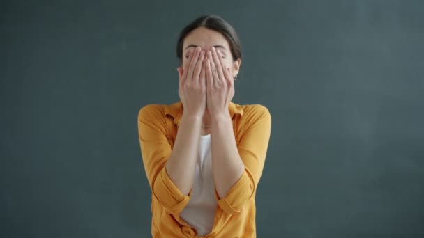 Zeitlupenporträt eines verspielten Mädchens, das sein Gesicht mit den Händen verdeckt und dann in die Kamera schaut, um Versteckspiel zu genießen — Stockvideo