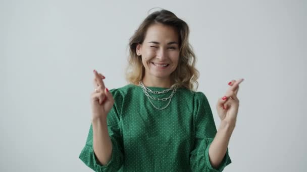 Retrato de menina feliz cruzando os dedos e sorrindo fazendo desejo no fundo branco — Vídeo de Stock