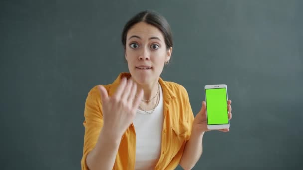 Portré fiatal hölgy gazdaság chroma kulcs zöld képernyő okostelefon és mutatja hüvelykujj-up kéz gesztus — Stock videók