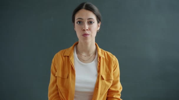 Slow motion portrait of confused young lady rolling eyes then looking at camera with shy face — Stock Video