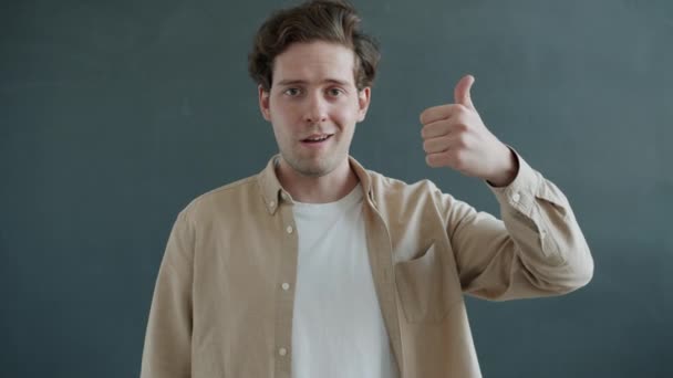 Portretul unui tânăr care arată degetele în sus, apoi degetele în jos gestul mâinii și se uită la camera foto cu dezamăgire — Videoclip de stoc