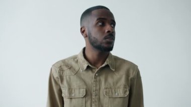 Afro-Amerikalı adamın portresi etrafa bakıyor sonra hava öpücüğü gönderiyor ve göz kırpıyor.