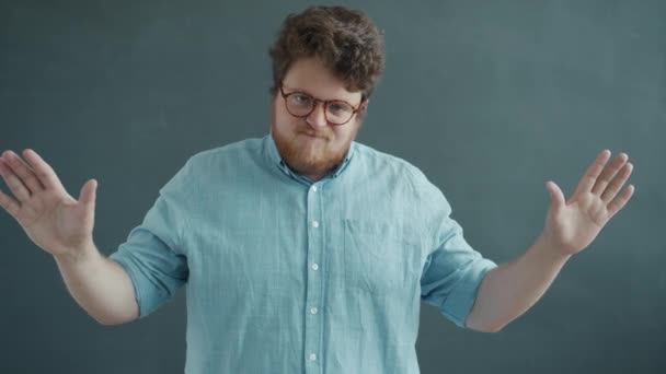 Serious guy crossing arms showing no gesture shaking head looking at camera on gray background — Stock Video