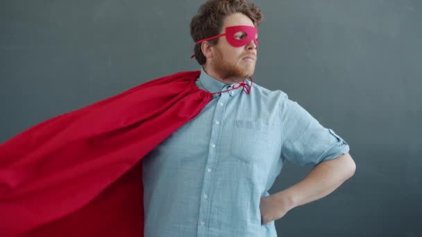Zeitlupenporträt eines lustigen Supermannes, der vor der Kamera steht, dann Maske fixiert und davonläuft — Stockvideo