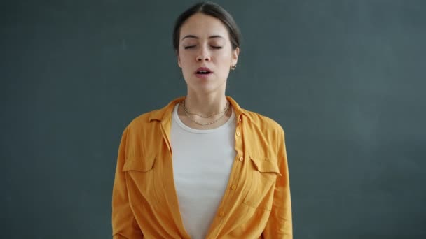 Movimento lento da bela mulher fechando os olhos e meditando sobre fundo cinza — Vídeo de Stock