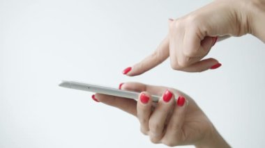 Beyaz arkaplanda akıllı telefon ekranına dokunan kadın elinin yavaş çekimde yakın çekim görüntüsü