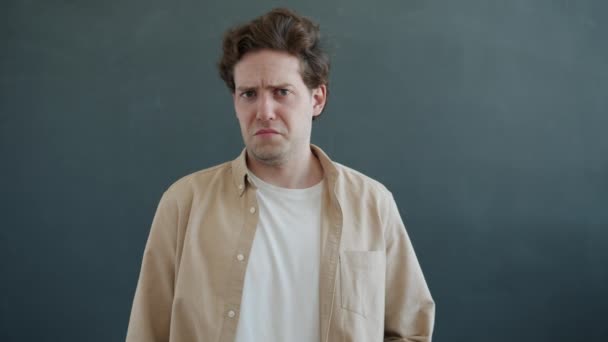Portrét znechuceného mladého muže se nakrčeným nosem a bez gesta na šedém pozadí — Stock video