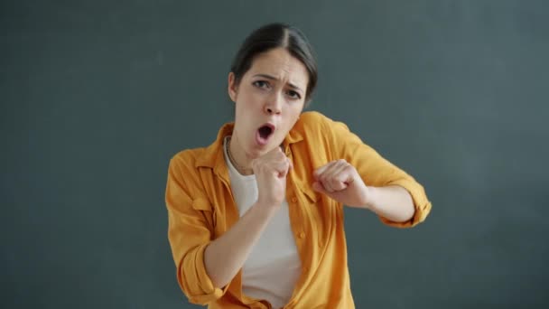 Retrato en cámara lenta de mujer joven bailando y cantando divirtiéndose sobre fondo gris — Vídeos de Stock