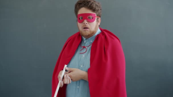 Portrét zábavného herce v superman kostým lízání obrovské lízátko a křik při pohledu do kamery — Stock video