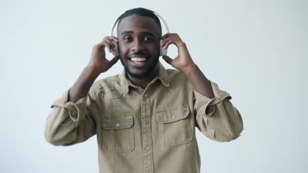 Slow motion portrait of African American student wearing headphones dancing on white background — Stock Video